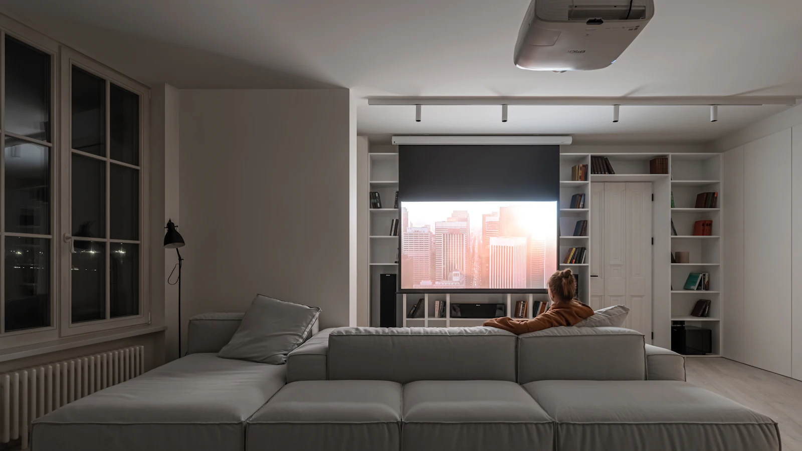 Person watching a projection screen in a bright living room