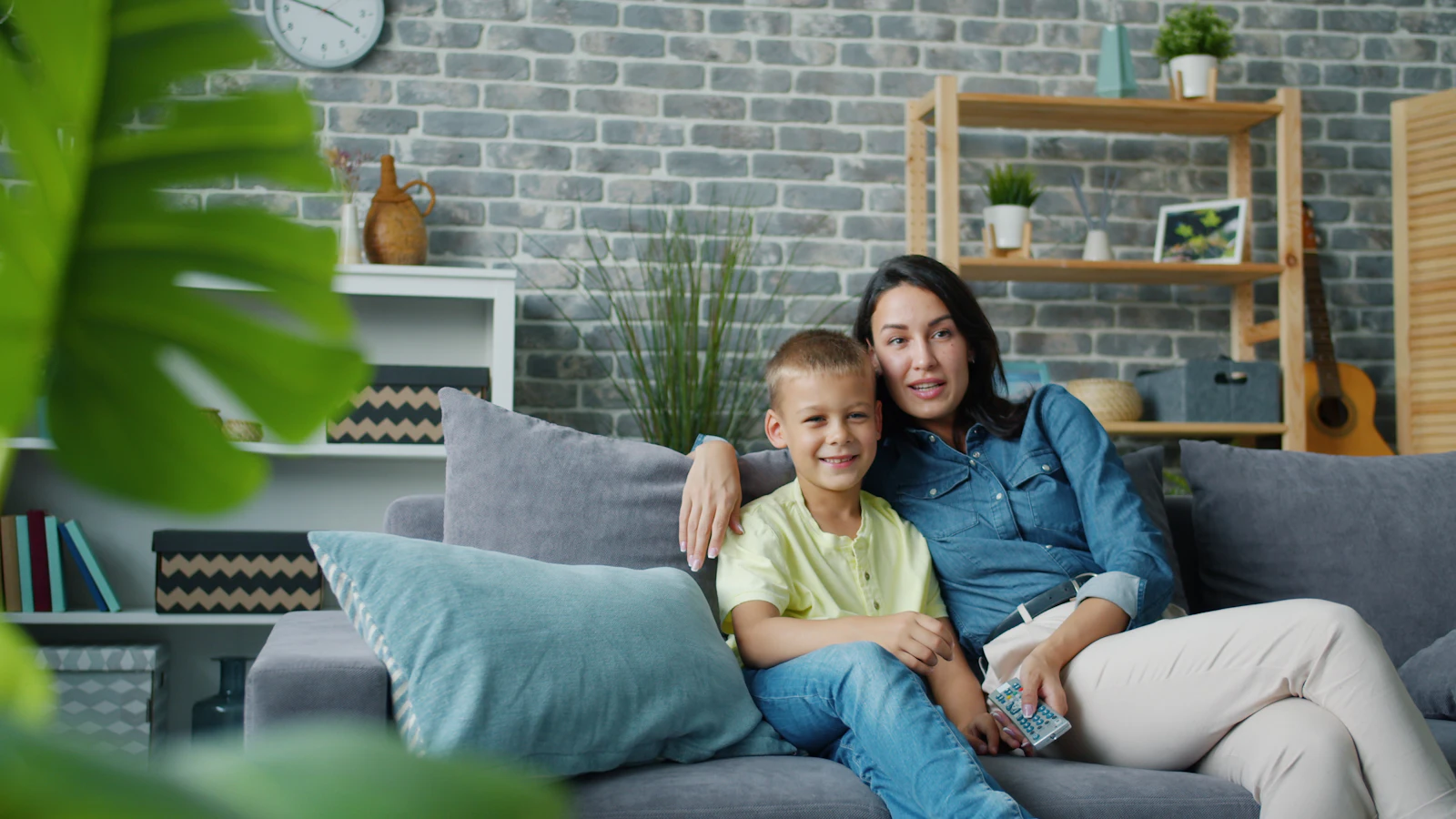 Mother and son sitting together on a couch watching TV