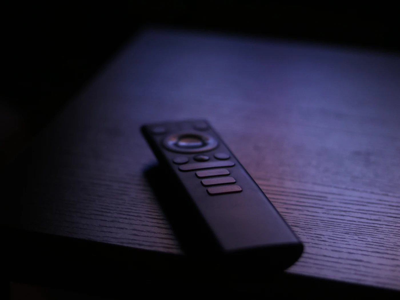 Streaming remote control resting on a dark wooden table